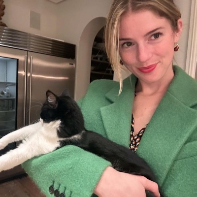 Maggie Elizabeth McGraw in a green suit carrying her pet cat.